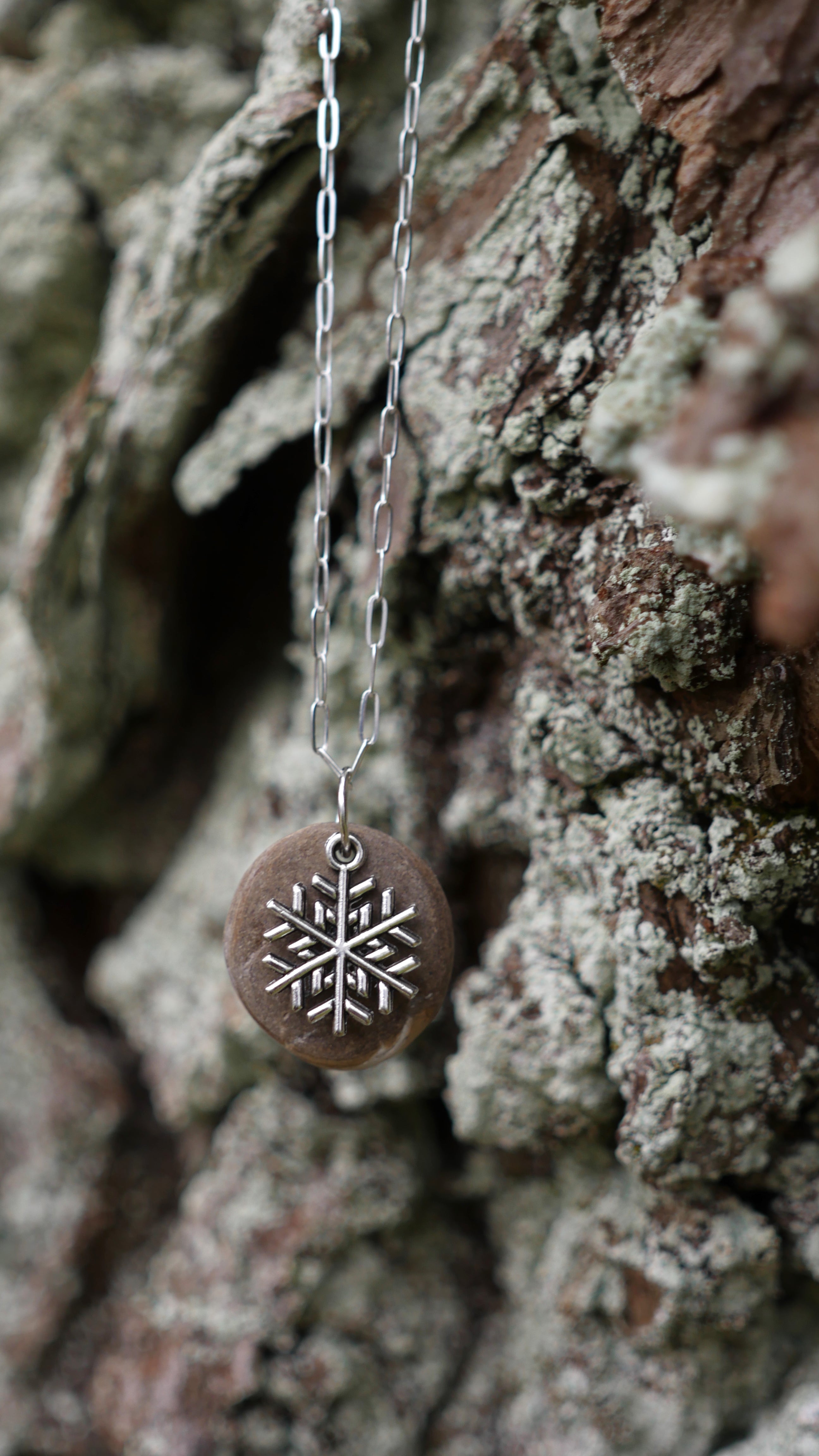 Silver plated snowflake charm on speckled stone on sterling silver paperclip chain