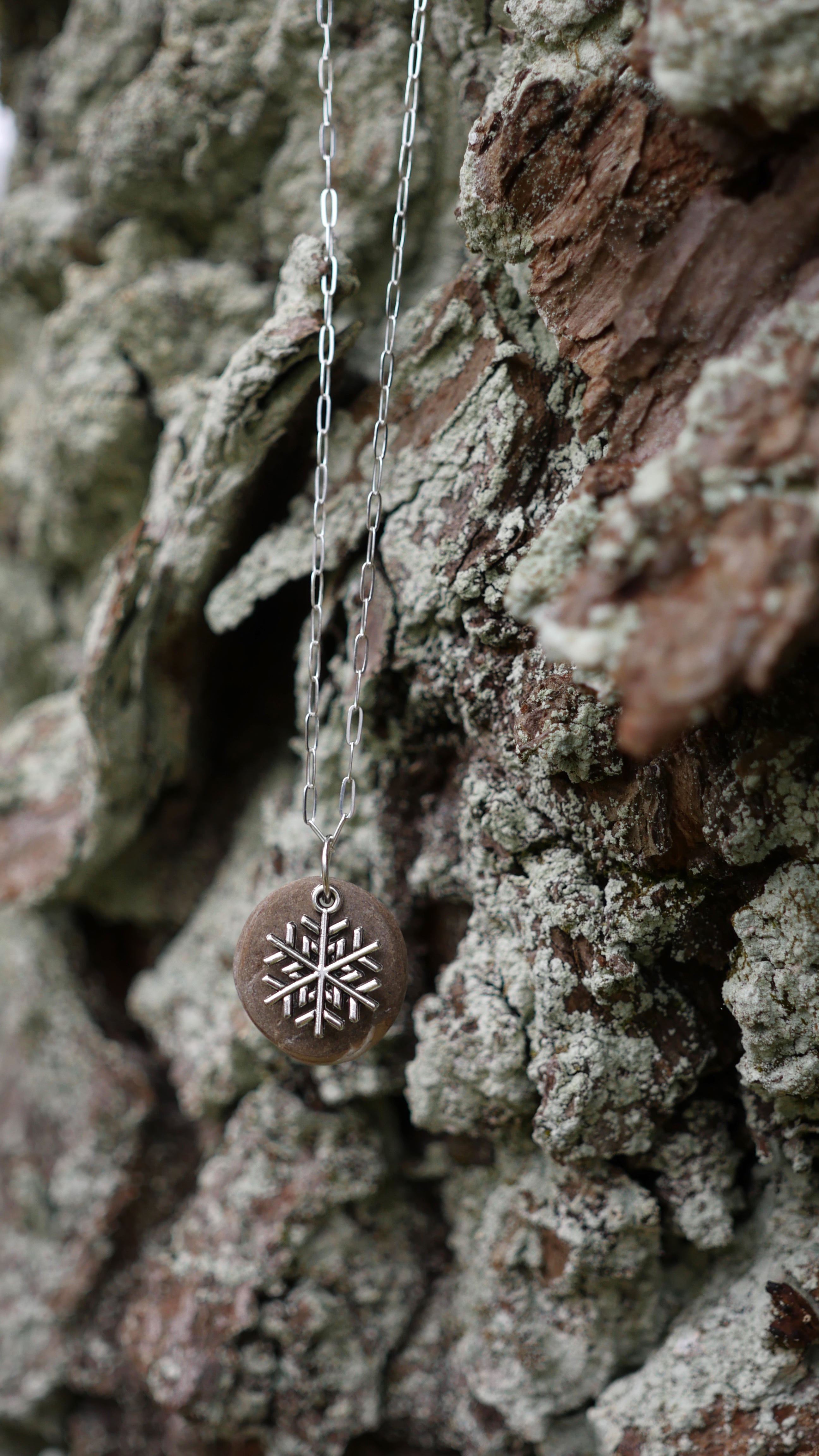 Silver plated snowflake charm on speckled stone on sterling silver paperclip chain